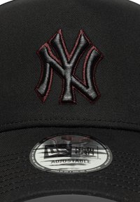 Cappello nero con logo dei New York Yankees ricamato in rosso scuro. Presenta una visiera curva e una fascia regolabile; texture liscia con un design aderente.