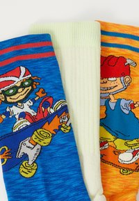 Three pairs of patterned socks: blue with a skateboard graphic, light green with vertical stripes, and orange with a character design.