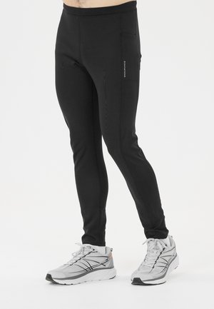 Svarta träningsbyxor i stretchmaterial med slim fit. Har sidofickor och platt midja, i kombination med grå löparskor.