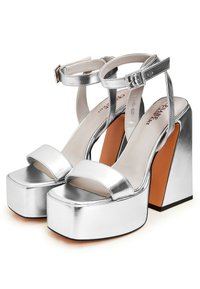 Sandalias de plataforma metálicas plateadas con tiras frontales anchas, cinturilla con hebilla y tacón cuadrado. Textura suave con un acabado brillante.