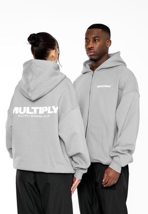Gray zip-up hoodie made of soft fabric, featuring large white "MULTIPLY" text on the back, with a relaxed fit and kangaroo pockets.