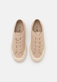 Beiga canvas sneakers med runda tår, en ribbad gummi sula och hål för snören. Har platta snören och en texturerad yta.