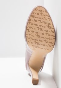 Talons hauts roses avec une finition brillante et une pointe pointue. La semelle présente une couleur beige avec un motif en relief "Tamaris" et une taille "37."