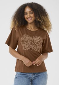 T-shirt en coton brun à manches courtes et col rond, ornée d'une broderie complexe de couleur claire dans un motif floral sur le devant.