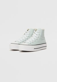 Höga sneakers i ljus mintgrön canvas med vita snören, gummitåhuvud och svarta randdetaljer på sulan. Texturerad sula.
