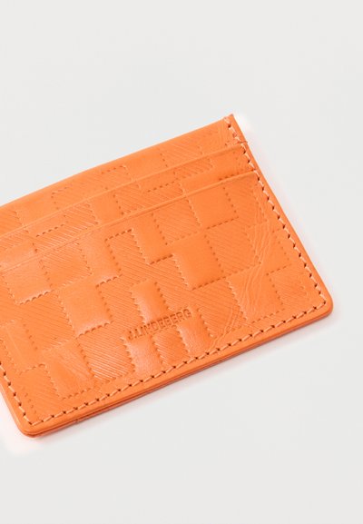 Πορτοκαλί δερμάτινη θήκη καρτών με υφασμένο καρό σχέδιο, τρεις θήκες για κάρτες και το λογότυπο "J.LINDEBERG" χαραγμένο στο μπροστινό μέρος.