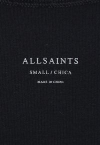 Schwarzes Stoffetikett mit weißem Text, der "ALLSAINTS", die Größe "SMALL/CHICA" und "MADE IN CHINA" am unteren Rand anzeigt. Der Text ist einfach und gut lesbar.