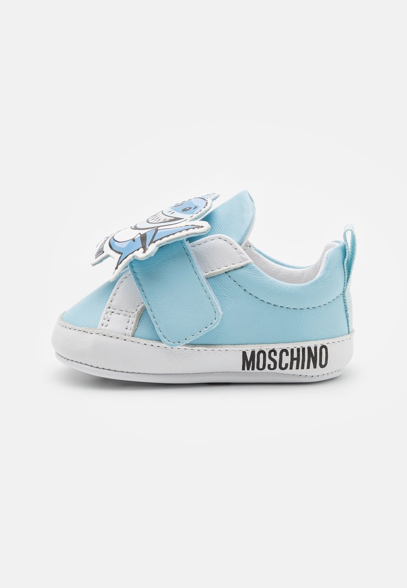 Basket en cuir bleu pour enfants avec des accents blancs, bande Velcro et un design de personnage sur la languette. Marque "Moschino" sur le talon.