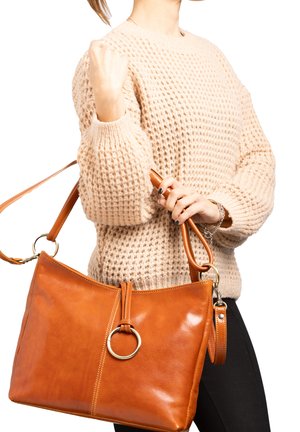 Borsa a mano in pelle marrone chiaro con forma rettangolare, texture lucida, grande anello decorativo sul davanti e tracolla regolabile.