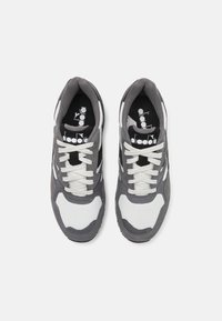 Gray and white athletic shoes with mesh and suede materials. Features include laces, padded collars, and a black and white logo on the insole.