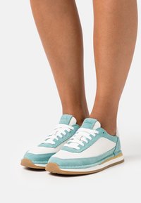 Sneaker azzurro chiaro e bianco realizzati in pelle e camoscio, con punta arrotondata, lacci bianchi e suola in gomma.