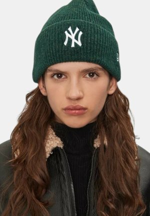 Beanie a coste verde con logo ricamato dei New York Yankees in bianco. Presenta una texture morbida e un design a punta.