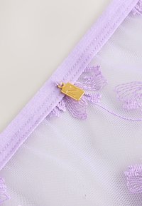 Vijolična čipkasta torbica s cvetličnim vezenjem, opremljena z vijoličnim zadrgo in zlatim zadrgovalnim potegom s podrobnostjo v obliki vtisnjene črke.