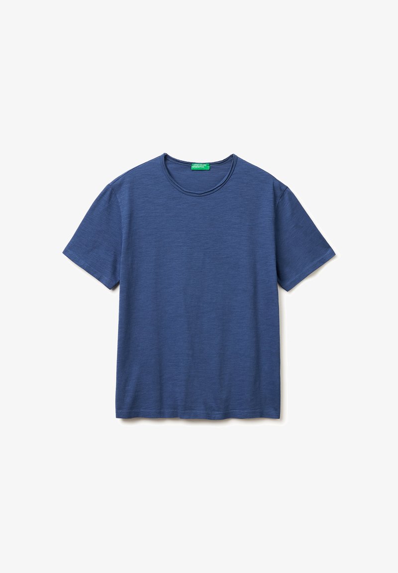 Camiseta azul lisa de manga corta y cuello redondo, con una etiqueta verde en el interior de la parte trasera del cuello, extendida sobre un fondo blanco.