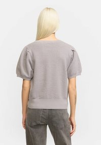 Pulover scurt, texturat, de culoare gri, cu mânecă scurtă, guler rotund și tiv elasticizat, asortat cu pantaloni gri cu talie înaltă.