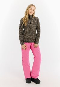 Sort og beige leopardmønstret fleece-top med lynlås krave, parret med klart pink vandtætte bukser og sorte støvler.