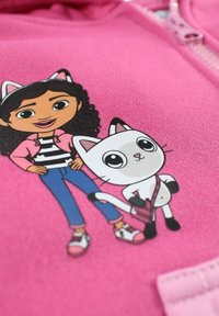 Sweat à capuche rose présentant un dessin cartoon d'une fille en veste rose et chemise rayée à côté d'un chat blanc aux accents noirs.