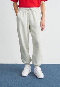 Hellgraue Jogginghose aus weichem Stoff, mit elastischem Bund und Kordelzug, Seitentaschen und Bündchen an den Knöcheln.