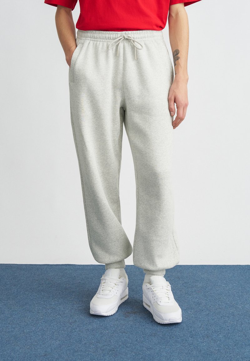 Hellgraue Jogginghose aus weichem Stoff, mit elastischem Bund und Kordelzug, Seitentaschen und Bündchen an den Knöcheln.