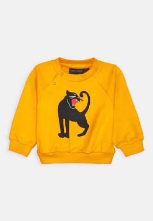 Sweat-shirt pour tout-petit à manches longues jaune avec un graphique de chat rugissant noir sur le devant, des poignets et un ourlet côtelés, et des boutons-pression près de l'encolure.