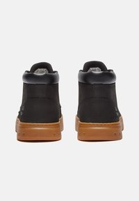 Svarta mockaskor i mid-top stil med svarta läderdetaljer, gummisulor och tonad sömnad. Har en vadderad krage för ökad komfort.