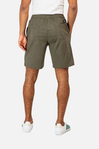 Olive green shorts with an elastic waistband, two back pockets, and a casual design, complemented by white sneakers with green accents.