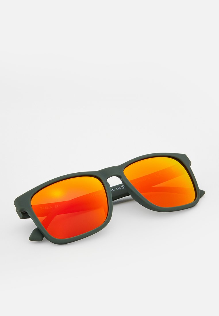Zielone matowe okulary przeciwsłoneczne w kwadratowym kształcie z lustrzanymi pomarańczowymi szkłami. Grube ramiona z widoczną marką po wewnętrznej stronie.