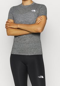 Gray short-sleeve T-shirt with a round neckline and a logo on the left chest, paired with black leggings featuring a white logo.