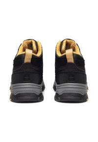 Czarne trampki typu high-top z teksturowanym materiałem, wyściółką w kolorze żółtym, oraz szarymi gumowymi podeszwami z żółtymi akcentami i pętelką z tyłu.