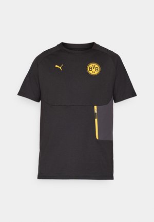 Camiseta negra de manga corta con acentos amarillos, que presenta un bolsillo con cremallera y un logo redondo en el pecho. Fabricada con un tejido suave.