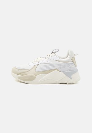 Hvid og beige atletiksko med tekstureret sål, mesh og syntetiske overdele, snørelukning og polstret krave på en ensfarvet baggrund.