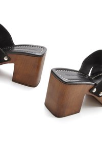 Black suede platform sandals with chunky wooden heels. Features white stitching and silver hardware accents. Open-toe design.