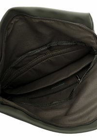 Intérieur de sac vert olive à texture lisse, comprenant plusieurs compartiments, une poche zippée et un détail de logo discret.