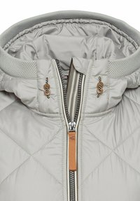 Hellgraue gesteppte Jacke mit hoch geschlossenem Kragen, auffälligem Reißverschluss mit orangefarbenem Akzent und strukturiertem grauen Besatz um die Kapuze.