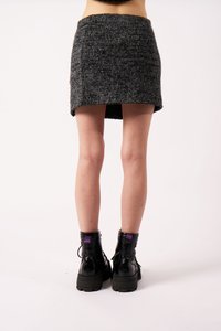 Γκρίζα πλεκτή μίνι φούστα με υφή, ψηλή μέση και ελαφρώς κυρτή άκρη. Συνδυασμένη με μαύρες μποτάκια με κορδόνια που έχουν μοβ λεπτομέρεια.