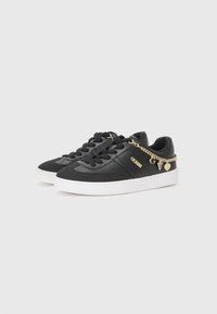 Svart sneakers laget av glatt lær, med en hvit gummisåle, snøring og en gullkjedeaccent med charms. Klassisk sportdesign.