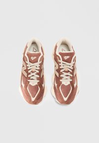 Baskets de sport marron et crème avec un dessus en daim texturé et en mesh, dotées de lacets épais, d'un col rembourré et d'une semelle épaisse.