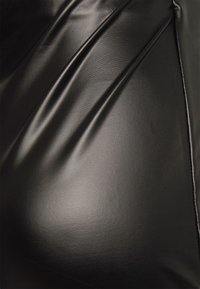 Tecidos pretos brilhantes com uma textura suave e pregas visíveis, apresentando uma aparência semelhante ao couro e um brilho subtil.