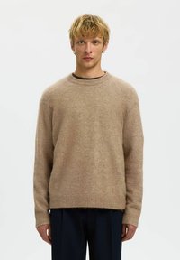 Beige gestrickter Pullover mit Rundhalsausschnitt, langen Ärmeln, gerippten Bündchen und Saum. Weiche Textur, leicht übergroße Silhouette.