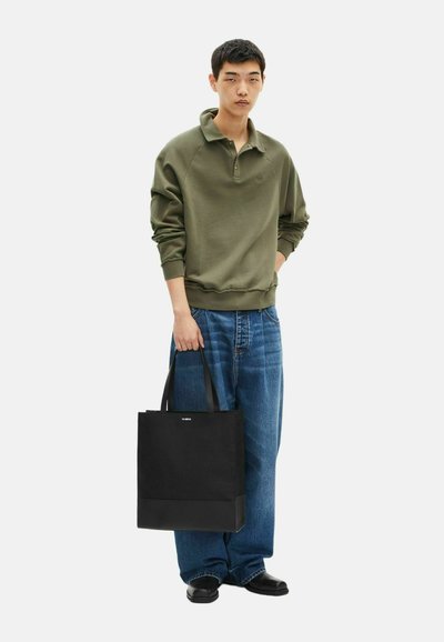 Zwarte totebag met dubbele korte handvatten, gemaakt van stevig materiaal, met een minimalistisch ontwerp en een klein logo op het voorpaneel.