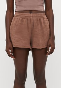 Shorts bruns texturés avec un waistband élastique et une coupe ample. Présente un tissu froissé pour plus de dimension et de confort.