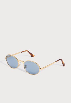 Lunettes de soleil à monture métallique dorée avec verres ovales bleus et branches écaille de tortue, équipées de plaquettes de nez réglables.