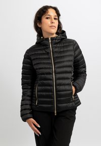 Giacca a piumino nera con cappuccio, caratterizzata da una texture trapuntata, dettagli con cerniera dorata e tasche laterali. Materiale liscio e leggero.