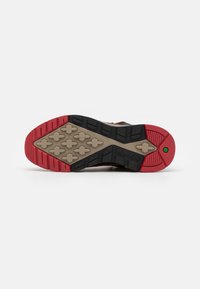 Sole bot Timberland s robustním designem v hnědé, béžové a červené barevné kombinaci, s texturovanými vzory a trakčními výstupky pro lepší přilnavost.