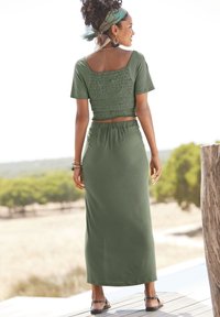 Olivgrünes zweiteiliges Outfit mit einem gesmokten Crop Top mit kurzen Ärmeln und einem passenden langen Rock mit elastischem Taillenbund.