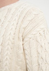Πουλόβερ με πλέξη καλώδιο σε εκρού χρώμα, με υφασμένους σχεδιασμούς πλεξούδας, μαλακή και χοντρή πλέξη, και στρογγυλή λαιμόκοψη.