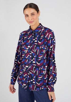 Overhemd met lange mouwen, met een levendig multicolored geometrisch patroon op een donkere achtergrond. Gemaakt van een soepele stof.