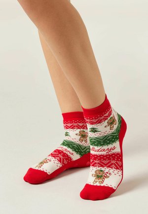 Červeno-bílé ponožky do kotníků s motivem perníčků, zelenými akcenty a texturovaným pleteným designem s vánočními motivy.