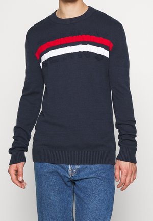 Marineblauer Strickpullover mit einem horizontalen roten, weißen und blauen Streifen über der Brust und erhabener Aufschrift "JEANS." Rippbündchen an den Ärmeln und am Saum.
