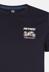 Camiseta de algodón azul marino con cuello redondo y mangas cortas. Presenta un diseño de motocicleta impreso en blanco y el logo "PETROL" en el pecho.